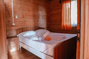 a bed in a wooden room with an orange on it at Plazhi Gjeneralit - Small Cabins - Bungalows - Apartaments - Villas - Suite in Kavajë