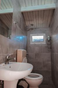 La salle de bains est pourvue d'un lavabo, de toilettes et d'une fenêtre. dans l'établissement Plazhi Gjeneralit - Small Cabins - Bungalows - Apartaments - Villas - Suite, à Kavajë