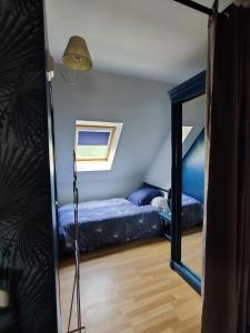 um pequeno quarto com uma cama e um espelho em Au Perchoir de la Chouette em Verneuil-en-Halatte
