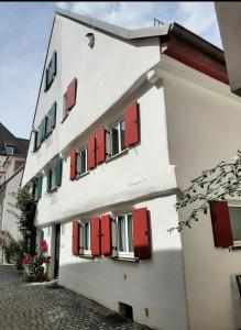 a white building with red shutters on a street at Altstadthaus Günzburg in Günzburg