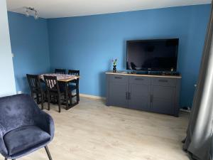 a living room with a tv and a table with chairs at Apartament Oksywie II in Gdynia