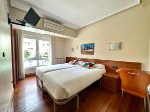 a bedroom with a large bed and a window at Pension Anoeta in San Sebastián