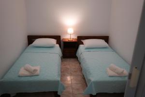 two twin beds in a small room with a lamp at Green Parrot Apartments in Frátsia