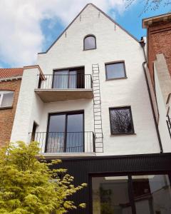 a white building with a balcony on top of it at Maison Brunon in Bruges +75 photos