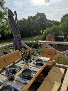 a wooden table with plates and a umbrella on a deck at Mazuria Inulec in Mikołajki