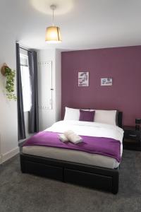 a bedroom with a large bed with a purple wall at MMR Homes in Carlisle
