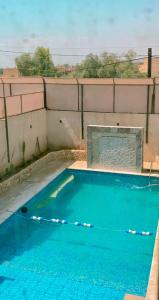 a swimming pool with blue water in front of a wall at Celina's farm in Al Rama