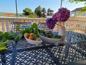 two bowls of fruit and flowers on a table at Olive Garden in Posedarje