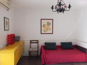 1 dormitorio con cama roja y lámpara de araña en Timo Bokelski, en Donji Stoliv