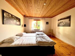 a bedroom with a large bed with a wooden ceiling at Sjönära lantgård i Bergslagen in Skinnskatteberg