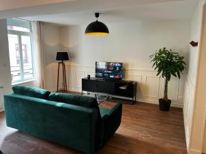 a living room with a green couch and a tv at Appartement Le Sithiu in Saint-Omer