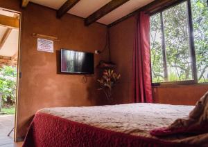 1 dormitorio con 1 cama y TV en la pared en Hotel Chalets Los Volcanes en Alajuela