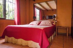 a bedroom with a bed with a red and white blanket at Hotel Chalets Los Volcanes in Alajuela