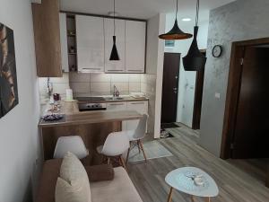 uma cozinha com armários brancos e uma mesa e cadeiras em Apartman ELENA em Jagodina