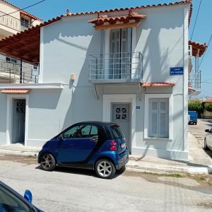 a small blue car parked in front of a white house at Apartments in Amarynthos - Evoia in Amarynthos