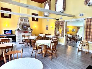a restaurant with tables and chairs and a fireplace at Ceilidh Country Lodge in Baddeck