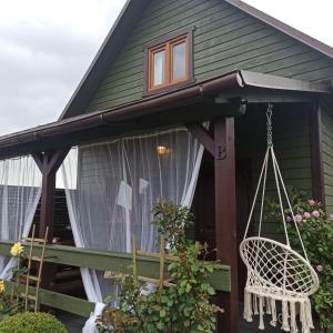 a house with a porch with a swing at Słoneczne Tarasy in Sasino