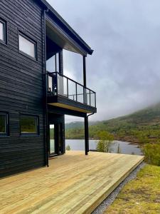 a house with a wooden deck next to a lake at Fjellsætra Alpegrend in Sykkylven