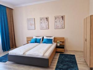 a bedroom with a large bed with blue pillows at ORI Classy Apart Malul Mureșului in Arad