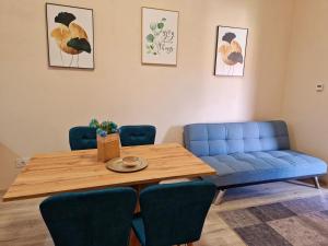 a dining room table with blue chairs and a blue couch at ORI Classy Apart Malul Mureșului in Arad