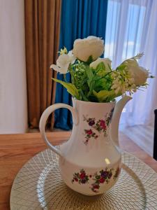 un jarrón blanco con flores en una mesa en ORI Classy Apart Malul Mureșului en Arad