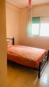 ein Schlafzimmer mit einem Bett in einem Zimmer mit einem Fenster in der Unterkunft Cartier El MANAR El jadida CITY in El Jadida