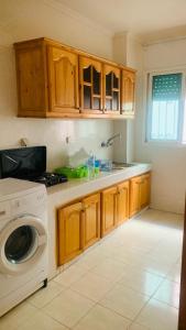 a kitchen with wooden cabinets and a washing machine at Cartier El MANAR El jadida CITY in El Jadida