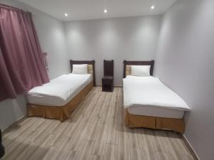 two beds in a small room with wooden floors at عاليا للشقق والاجنحة المفروشة in Al Khobar