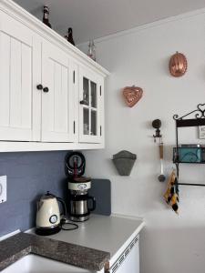 eine Küche mit weißen Schränken und einer Kaffeemaschine auf der Theke in der Unterkunft Appartement Hüttenzauber in Sankt Englmar in Sankt Englmar