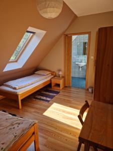PłaskaにあるSosnowy Młodnikのベッドと窓が備わる屋根裏部屋