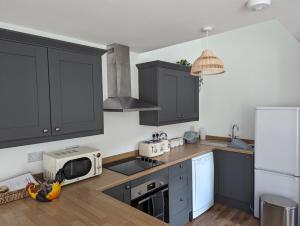 a kitchen with black cabinets and a white refrigerator at Myrtle Stables - converted, self-contained, countryside in Hernehill