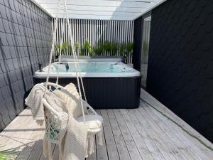a swing on a deck with a bath tub at Summer House-Nowoczesne domki z jacuzzi i ładowarką do samochodu in Wrzosowo