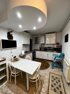 a large kitchen with a white table and chairs at Apartament Confort - Baile Olanesti in Băile Olăneşti