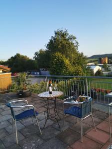 eine Terrasse mit 2 Stühlen und einem Tisch mit einer Flasche Wein in der Unterkunft Haus mit schöner Aussicht WG in Münsingen