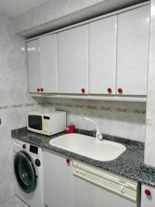 a kitchen with a sink and a microwave at Apartamento Deluxe El Camino in Alcalá de Henares