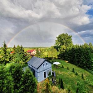 un arco iris sobre una casa blanca en una colina en Vitalny Domek z ogrodem nad jeziorem, 10 min od Mrągowa en Ruska Wieś