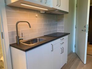 cocina con fregadero y armarios blancos en Central 1 bedroom apartment NB!! Small room, en Oslo