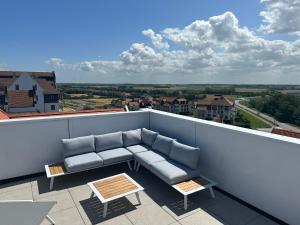 a couch on a balcony with a view of a city at Penthouse in Badhuis Cadzand in Cadzand
