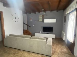 sala de estar con sofá y reloj en la pared en Acogedora casa en Onís - Cangas de Onis, en Avín