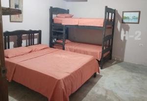 two bunk beds with orange sheets in a room at Villas del Mar Hostal in Cañas