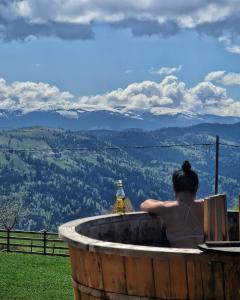 a woman sitting in a jacuzzi tub with a view at Cabana Dor de Apuseni in Cîmpeni