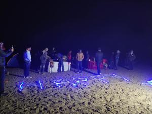 Un groupe de personnes autour d'une table dans le sable dans l'établissement Jhoomke camping and water sports adventure, à Auraiya