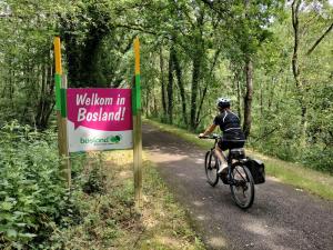 a person riding a bike on a trail next to a sign at Bosrand81 in Hechtel