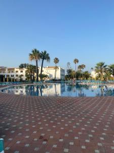 une grande piscine avec des palmiers et de l'eau dans l'établissement Beach House Golden Club, à Cabanas de Tavira