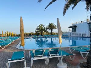 una piscina con sillas y sombrillas en un complejo en Beach House Golden Club, en Cabanas de Tavira