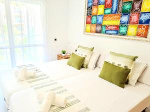 a white bedroom with a large white bed with green pillows at Apartamento 3 dormitorios Malaga (Teatinos) in Málaga