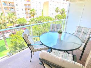 a glass table and chairs on a balcony with a view at Apartamento 3 dormitorios Malaga (Teatinos) in Málaga