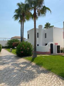 ein Haus mit zwei Palmen und einem Bürgersteig in der Unterkunft Beach House Golden Club in Cabanas de Tavira