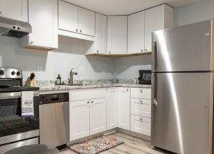 La cuisine est équipée de placards blancs et d'un réfrigérateur en acier inoxydable. dans l'établissement The Cozy Garden, à Marietta