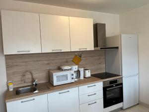 cocina con armarios blancos, fregadero y microondas en Apartments Zahtila - Berto en Rabac